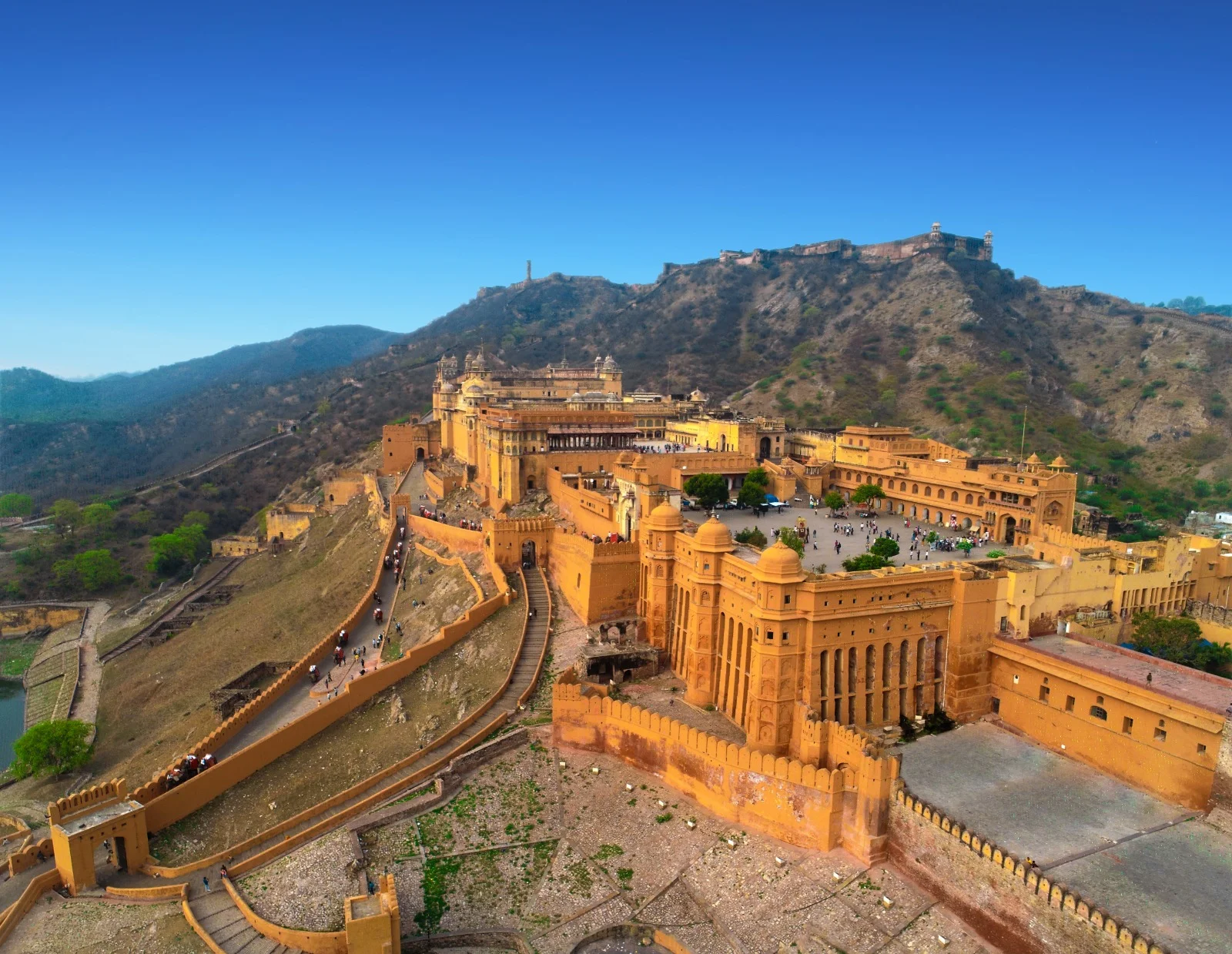 Wide-angle view of the historic golden-walled Amber Fort perched on a hill in Jaipur, Rajasthan.
